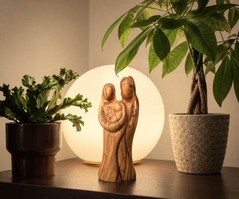Una imagen de la Sagrada Familia junto a plantas y una lámpara.